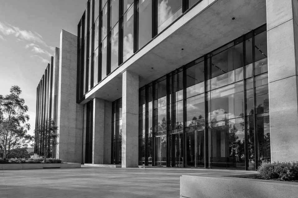 Black-and-white architectural study of a contemporary glass and concrete office building.
