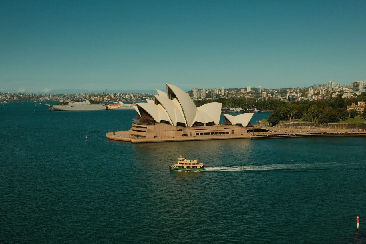 Sydney Opera House beside the harbour, with a ferry in the foreground